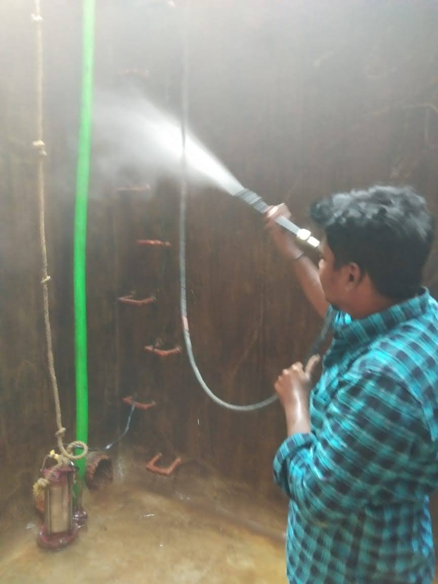 Technician pressure washing the interior walls of a residential water sump during a Hemavathi cleaning job
